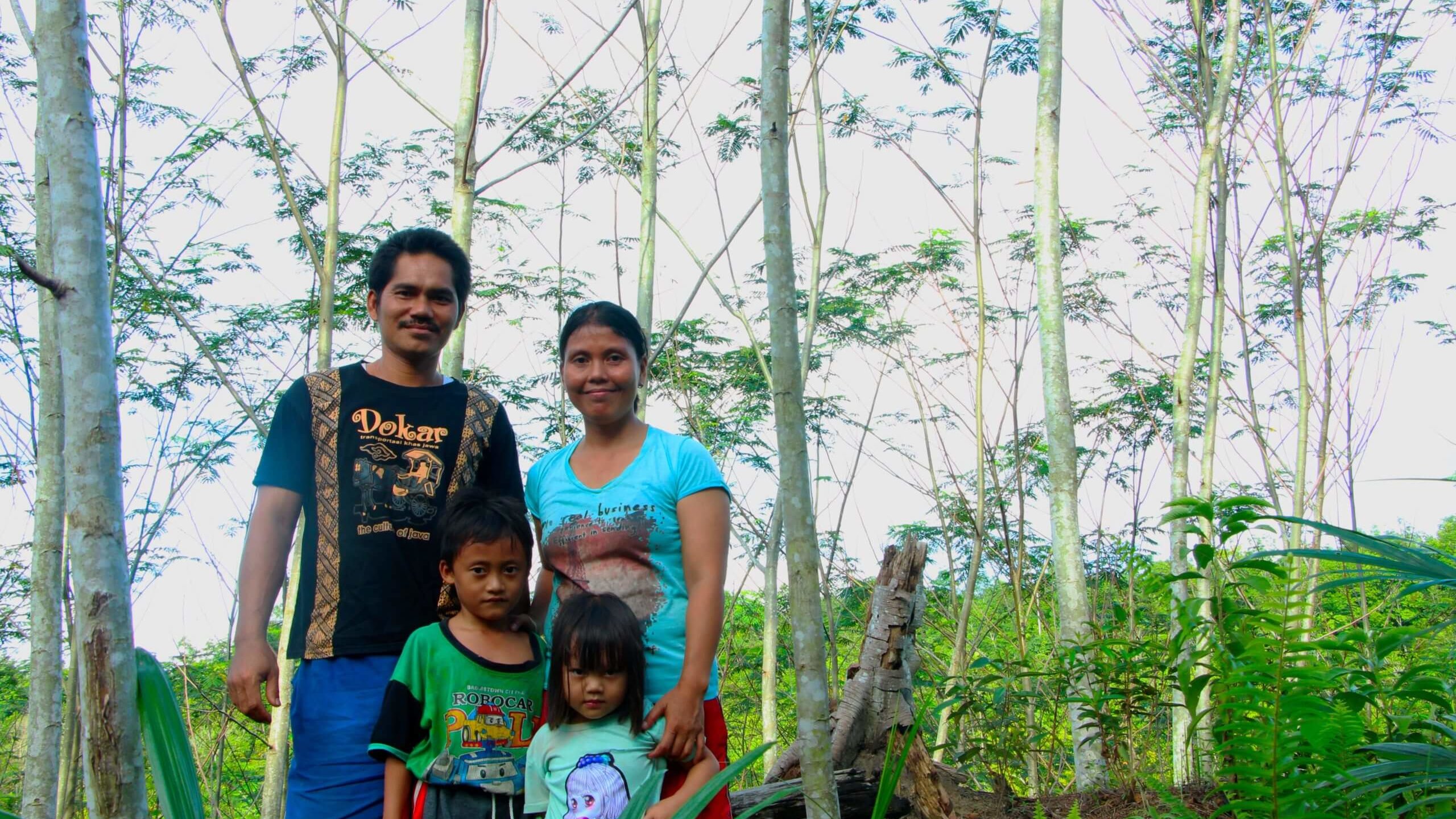 Kleinbauer steht mit seiner Familie im jungen Sengon-Wald - Geschichte eines mutigen Kleinbauern