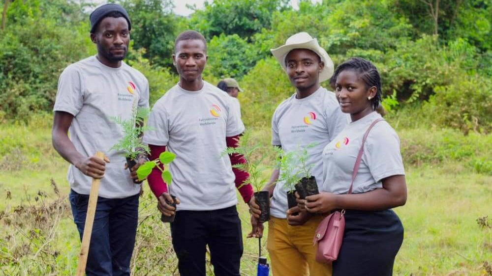 Four people with fairventures shirts carry seedlings